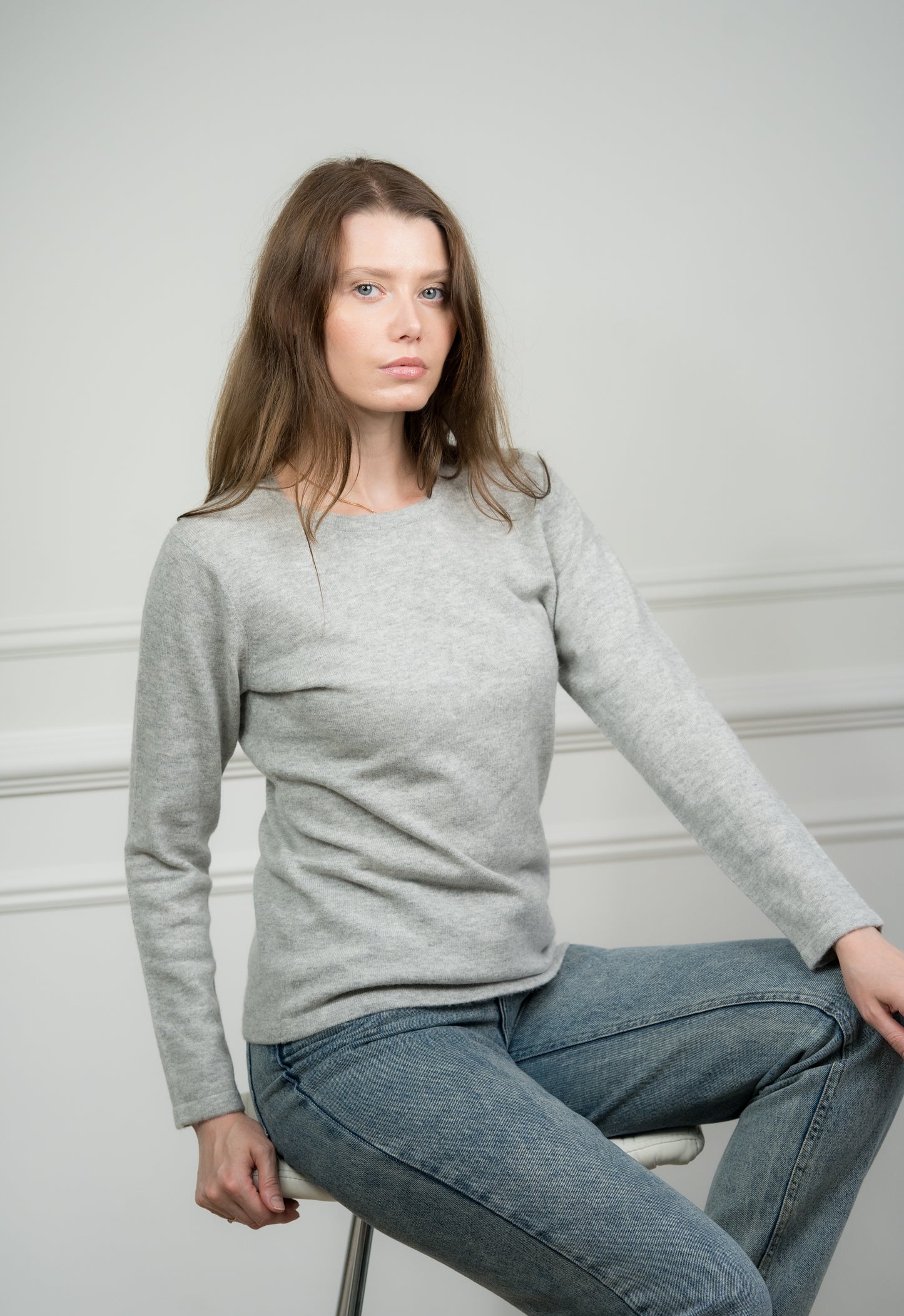 Model wearing Caprus Cashmere's pure cashmere crew neck jumper in light grey, showcasing its classic design and soft texture.