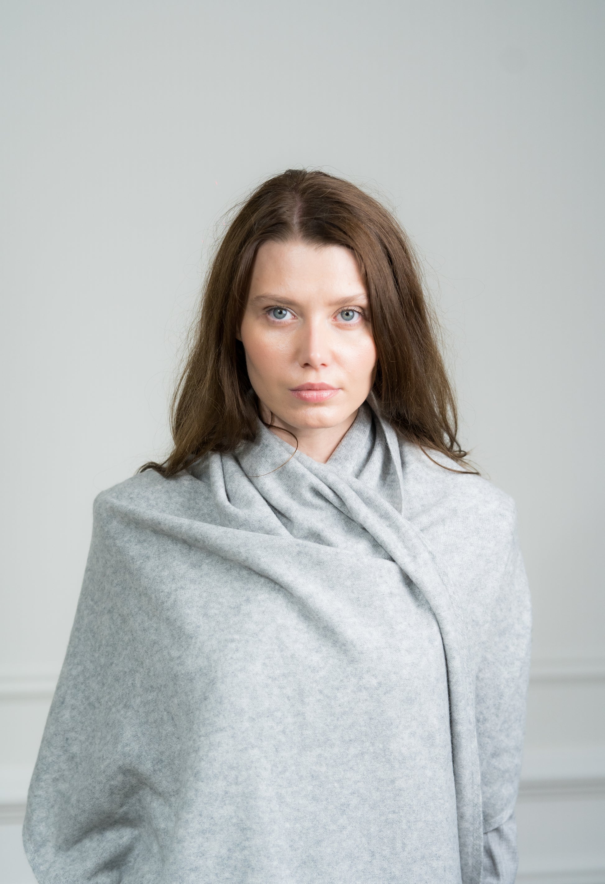 Model draping the Silver Travel Wrap over shoulders, illustrating its versatility as a women's scarf and travel wrap.