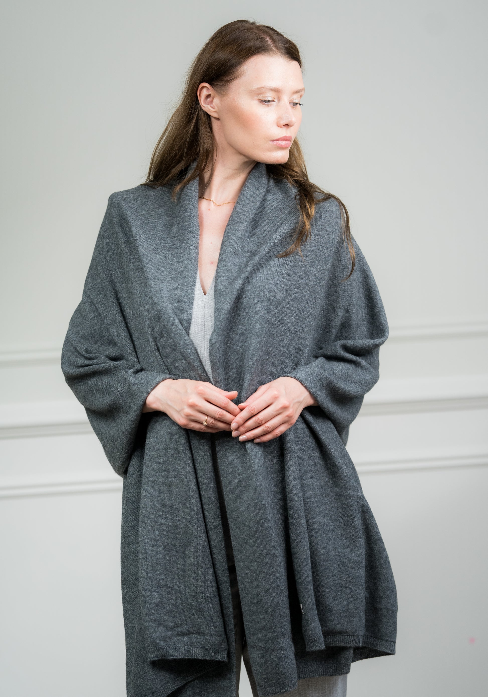 Model draping the Charcoal Travel Wrap over shoulders, illustrating its use as a cozy travel accessory and stylish wrap.