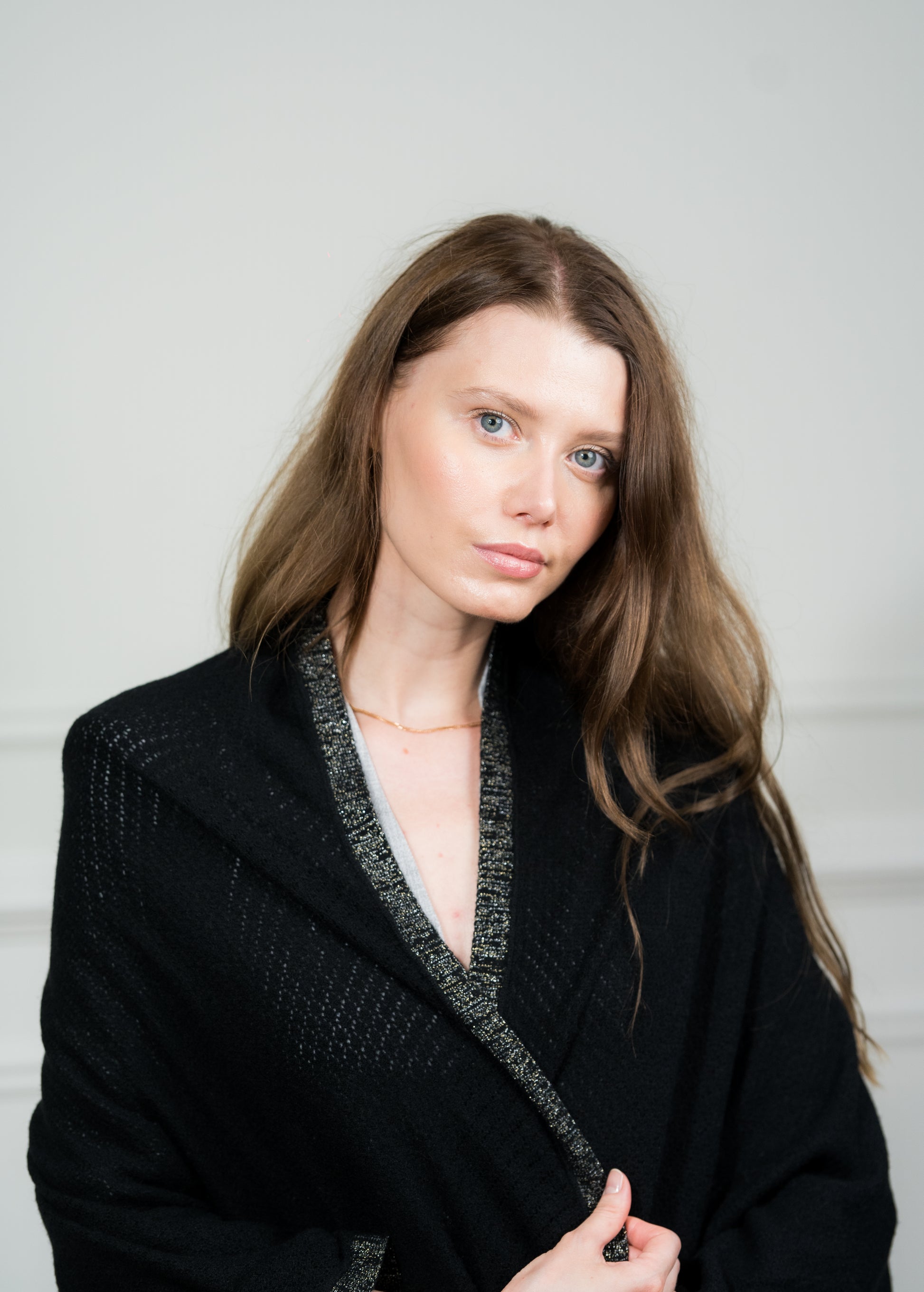 Detailed view of the Black Pointelle Wrap, featuring its breathable pointelle knit and elegant fringed edges, perfect for travel or layering.