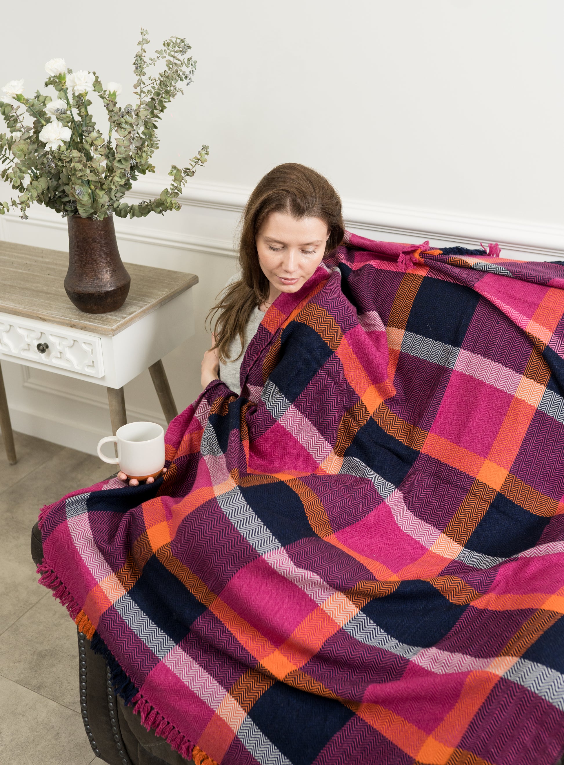 Caprus Cashmere's Vibrant Plaid Wool Throw displayed on a sofa, showcasing its bold plaid pattern and rich colors, perfect for adding a cozy and stylish touch to any living space.