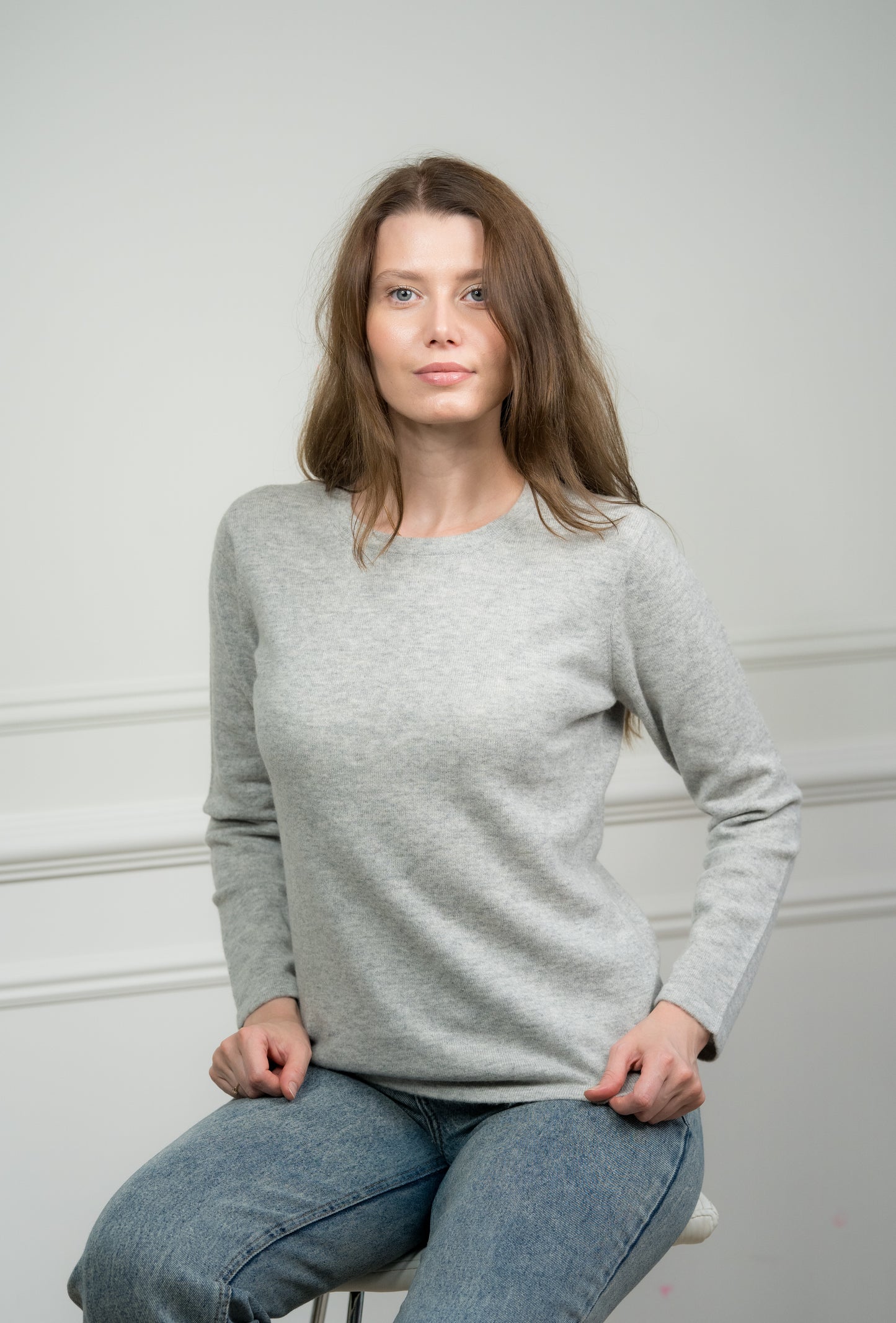 Close-up of the light grey crew neck jumper on a model, highlighting the fine knit and luxurious cashmere material.