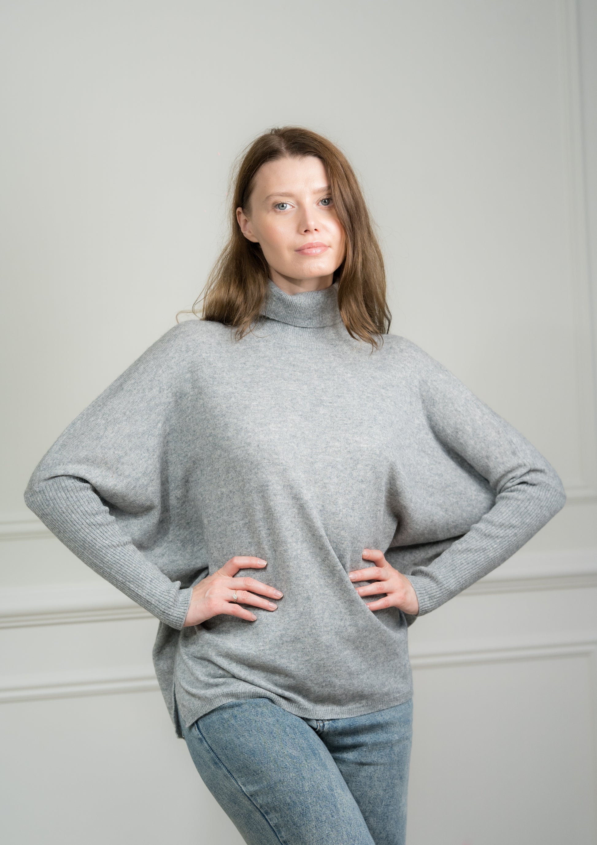 Model pairing the light grey crew neck jumper with jeans, illustrating its versatility for both casual and formal occasions.