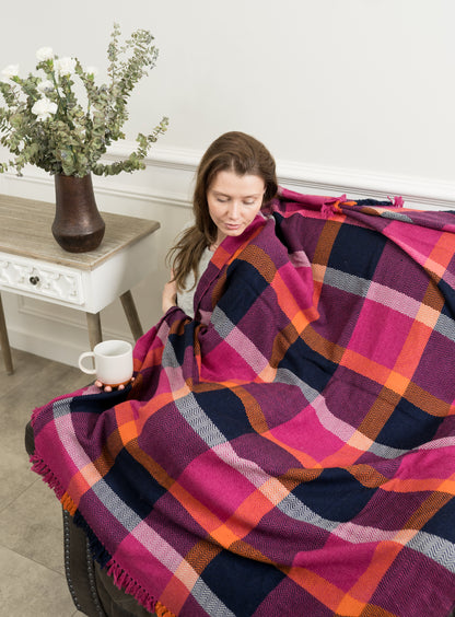 Caprus Cashmere's Vibrant Plaid Wool Throw displayed on a sofa, showcasing its bold plaid pattern and rich colors, perfect for adding a cozy and stylish touch to any living space.